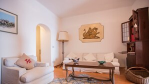 Una sala de estar con un sofá, una mesa de centro, una lámpara, un cuadro y una estantería.