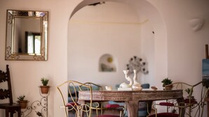 Un comedor con una mesa de madera rústica, sillas de metal y un espejo en la pared.