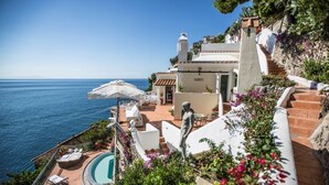 Una villa frente al mar con piscina, zona de estar exterior y una estatua.