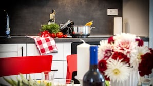 A kitchen with a red and white checkered towel, a pot with pasta, a bottle of wine, and a vase of flowers on the counter. - Nel Centro City Apartment (Rovinj)