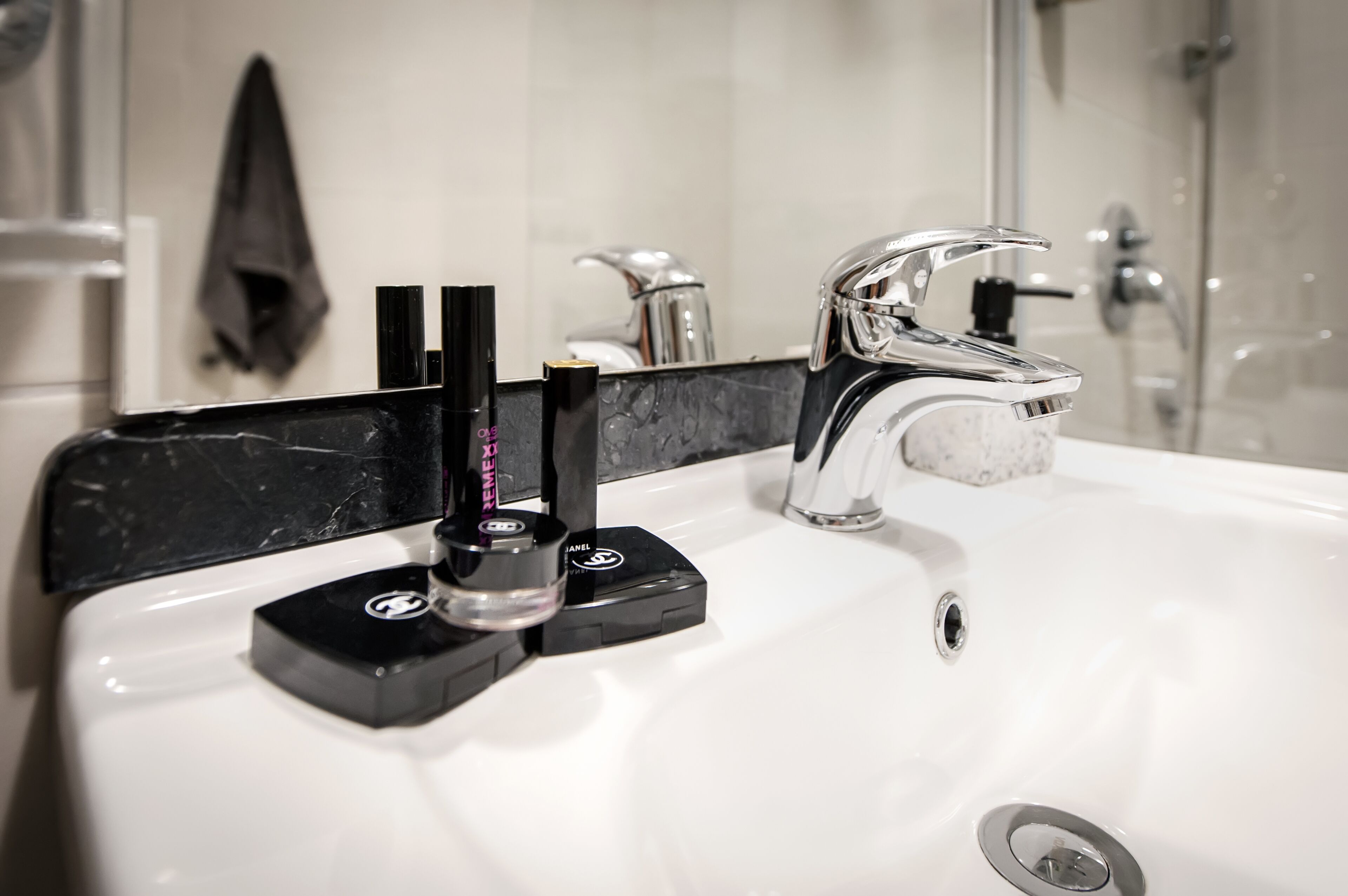 A bathroom with a white sink, a black soap dispenser, and a chrome faucet.