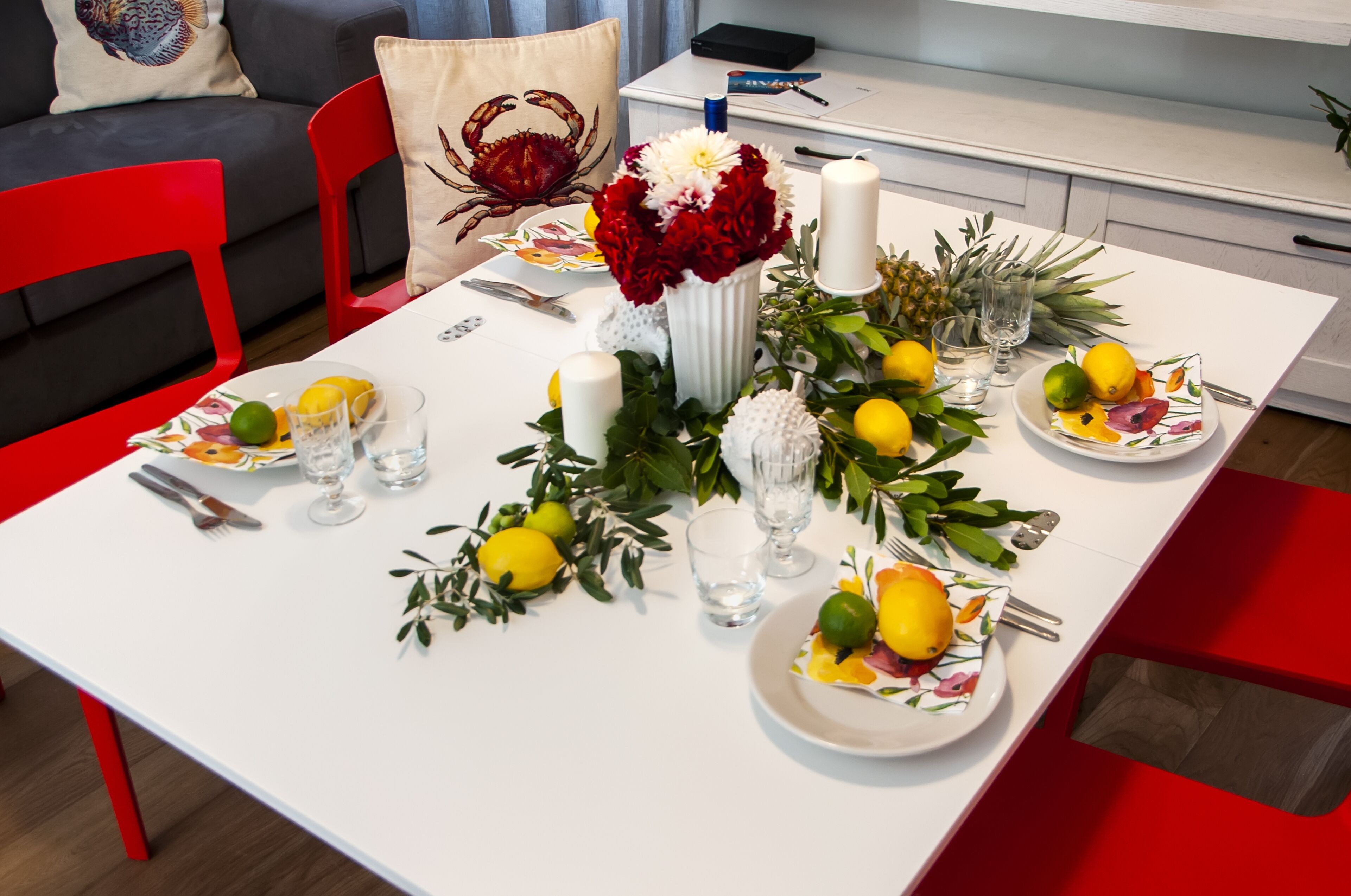 Une table à manger dressée avec des assiettes, des couverts, des verres et un centre de table composé de fleurs et de bougies.