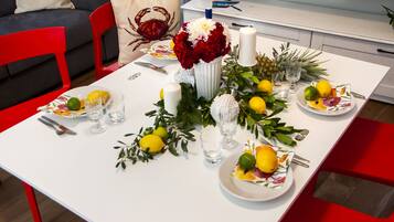 Une table à manger dressée avec des assiettes, des couverts, des verres et un centre de table composé de fleurs et de bougies.