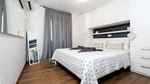 A bedroom with a bed, a mirror, a wardrobe, and a window with curtains. - Nel Centro City Apartment (Rovinj)