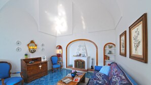Ein geräumiges Wohnzimmer mit Kamin, blauen Sesseln, einer hölzernen Kommode und einem Sofa.