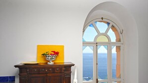 Quarto com um armário de madeira, parede amarela texturizada e janela com vista para o mar.