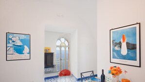 Um corredor com piso ladrilhado, um guarda-chuva vermelho e obras de arte emolduradas nas paredes.