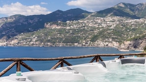 Ein Whirlpoolbereich mit Blick auf eine Küstenstadt und Berge im Hintergrund.