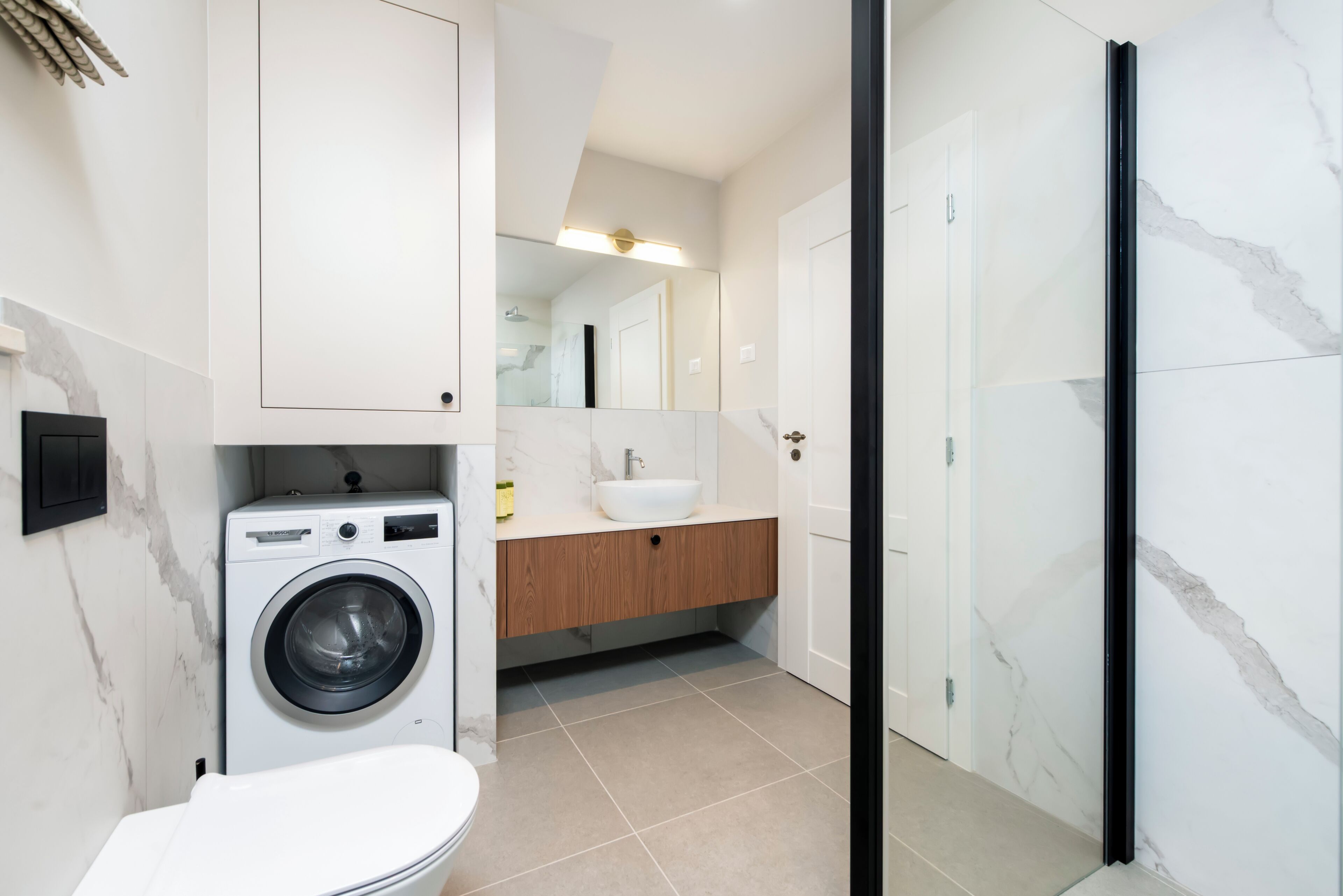 Un baño moderno con lavadora, lavamanos y ducha.