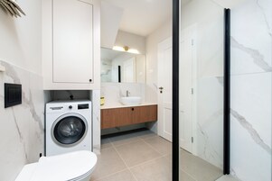 Un baño moderno con lavadora, lavamanos y ducha.