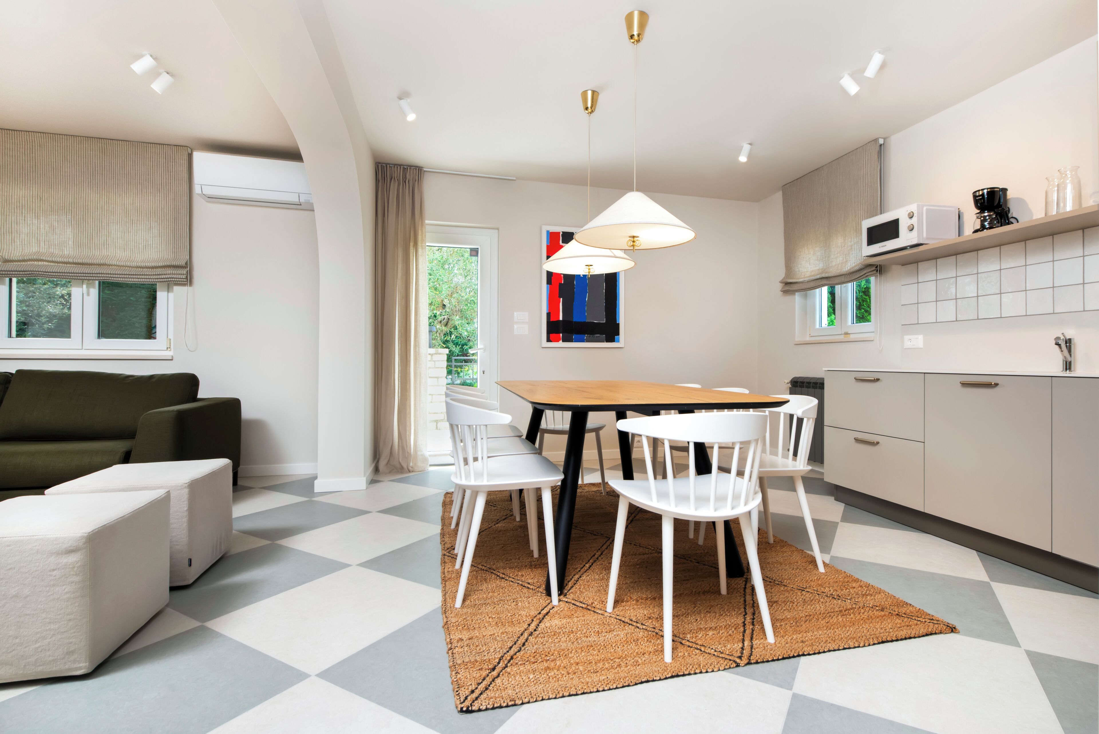 Eine moderne Küche mit Essbereich, weißen Stühlen, einem Holztisch und einem karierten Boden.