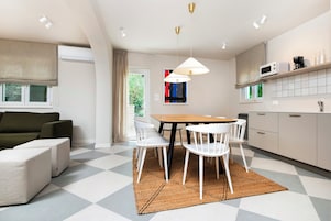 Eine moderne Küche mit Essbereich, weißen Stühlen, einem Holztisch und einem karierten Boden.