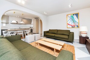 Un salon moderne avec un canapé, une table à manger et une cuisine en arrière-plan.