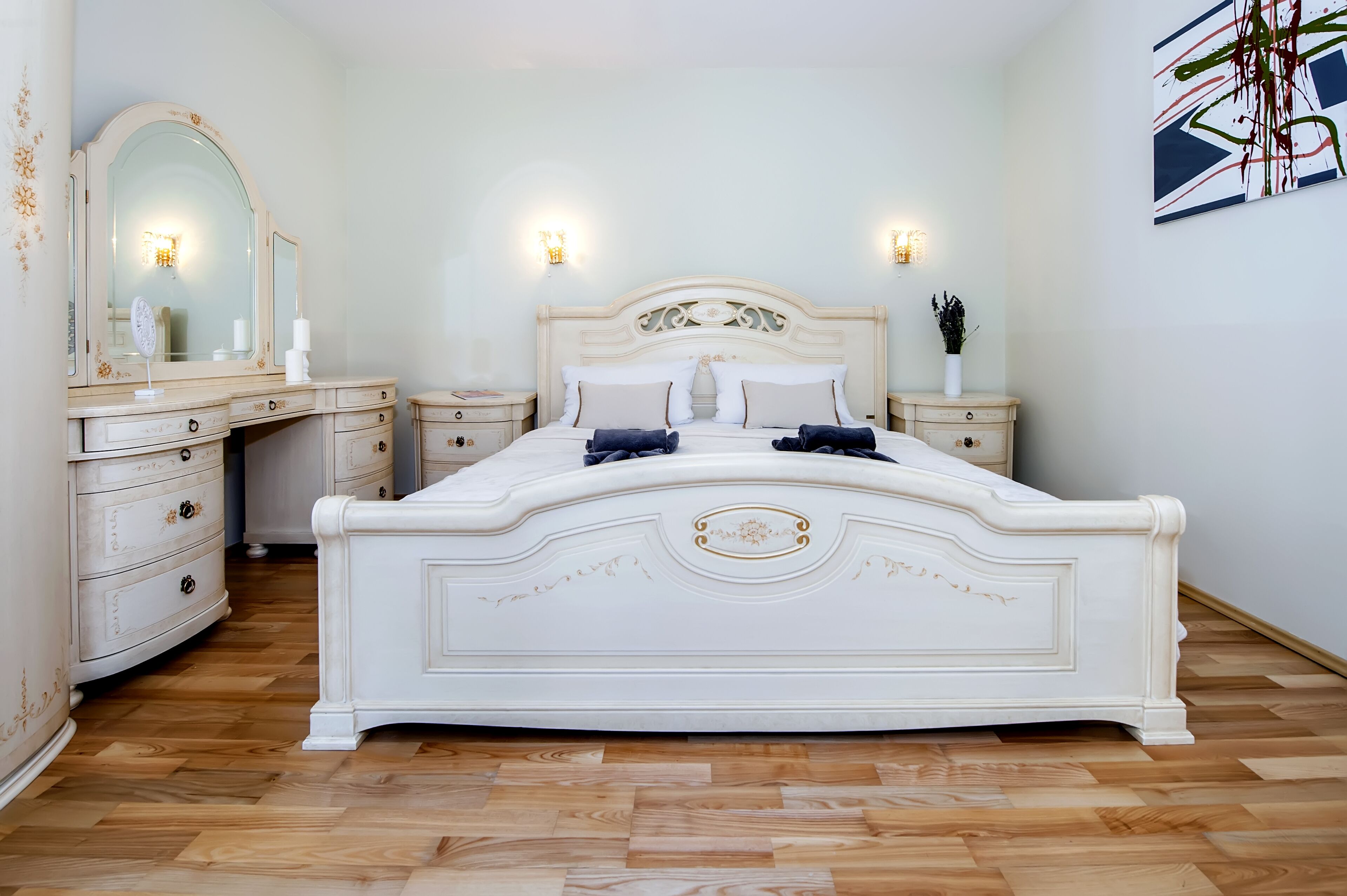 A bedroom with a large bed, a dresser, and a mirror.