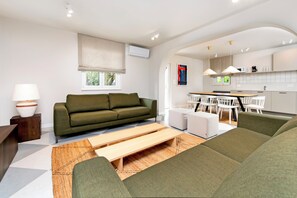 Un salon moderne comprenant un canapé, une table basse et un coin repas avec des chaises.