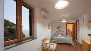 Ein Schlafzimmer mit Bett, Stuhl, Kommode und Meerblick.