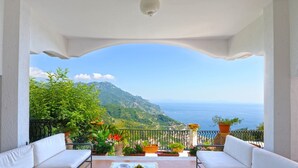 A balcony with white furniture, potted plants, and a view of the sea and mountains. - Lo sguardo sul mare, Luxury Ravello Villa, Private Pool, Great View, parking (Ravello)