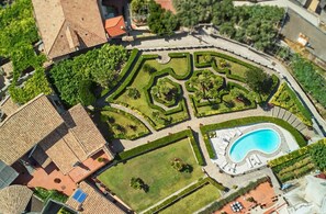 An aerial view of a landscaped area with a swimming pool, pathways, and various garden sections.