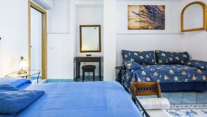 Um quarto com cama, escrivaninha, cadeira e um quadro na parede.