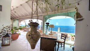 A sunlit patio with a stone wall, a hanging vase, and a view of the sea. - Villa Cindarella, Exclusive Property in Positano, private jacuzzi, near beach! (Positano)