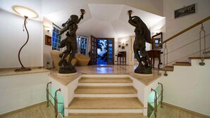 Un magnifique escalier, flanqué de deux statues de chaque côté, mène à une pièce bien éclairée qui offre une vue sur l’extérieur.