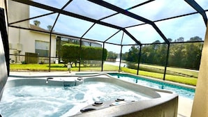 Ein Whirlpoolbereich mit Blick auf ein Schwimmbad und einen angelegten Garten.
