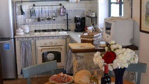 A kitchen with a dining table set for two, a stove, and various kitchen appliances. - Noce, Characteristic chalet in Umbria with SPA, jacuzzi, garden, stunning view. (Piedicolle)