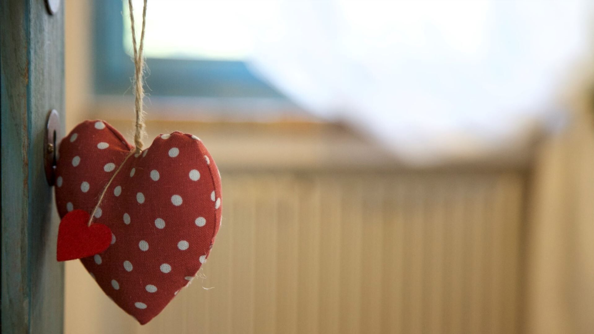 Una decoración de corazón rojo con lunares blancos colgada de un poste de metal.