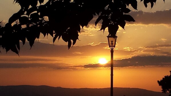 A sunset with a street lamp and silhouetted leaves. - Al boschetto, Luxury pool Villa in Umbria, SPA, outdoor space, garden, pizzaoven (Piedicolle)