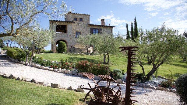 A stone villa with a garden, a rustic metal windmill, and a clear blue sky. - Al boschetto, Luxury pool Villa in Umbria, SPA, outdoor space, garden, pizzaoven (Piedicolle)