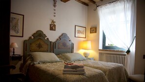 A bedroom with two beds, a window with sheer curtains, and a radiator. - Al boschetto, Luxury pool Villa in Umbria, SPA, outdoor space, garden, pizzaoven (Piedicolle)