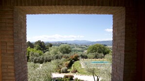 A view through a brick archway of a garden with a swimming pool, trees, and distant mountains. - Al boschetto, Luxury pool Villa in Umbria, SPA, outdoor space, garden, pizzaoven (Piedicolle)