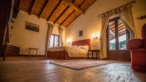 Relax in this inviting bedroom with a large bed, wooden floor, and a window with curtains.