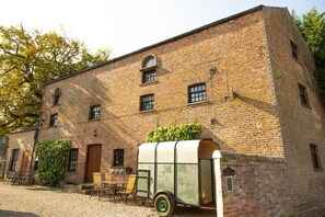 A brick building with a covered wagon parked in front.