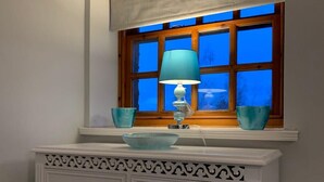A bathroom with a window, a white vanity with drawers, a blue lamp, and two blue bowls on the windowsill.