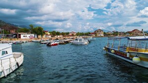 A marina with several boats docked, a waterfront building, and a mountainous backdrop.