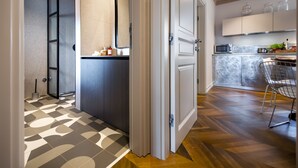 A modern kitchen with a herringbone wood floor, a built-in microwave, and a bar area with a chair. - Campitelli Design Apartment (Rovinj)