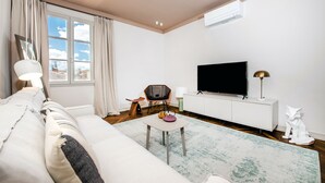 A modern living room with a sofa, a coffee table, a TV, and a decorative sculpture. - Campitelli Design Apartment (Rovinj)
