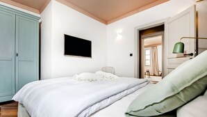 A bedroom with a bed, a TV, a green lamp, and a wardrobe. - Campitelli Design Apartment (Rovinj)