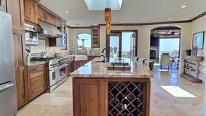 Una cocina amplia con armarios de madera, una isla central con espacio para vinos y vistas al exterior.
