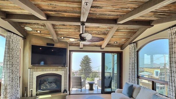 Un salón con chimenea, un sofá, un televisor y un balcón con vistas.