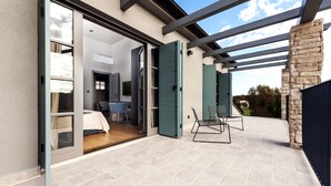 A modern house with a patio, sliding glass doors, and a stone wall. - Villa Renata with Pool and Sauna (Rovinj)