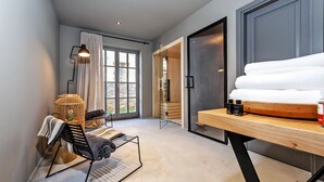 A modern hotel room with a large window, a cozy seating area with a chair and a small table, and a neatly made bed with towels and toiletries. - Villa Renata with Pool and Sauna (Rovinj)