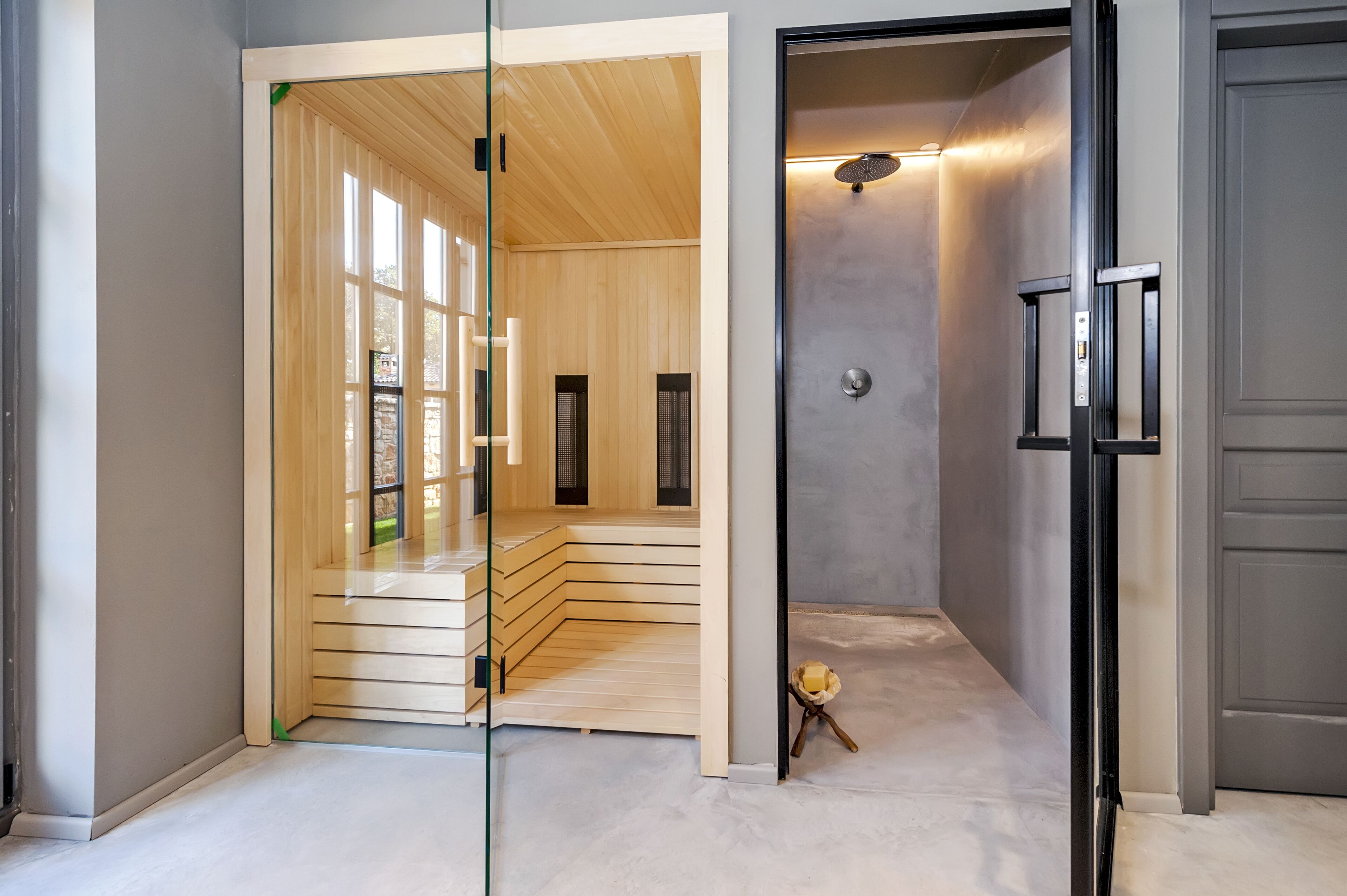 A modern interior with a glass partition, a sauna area, and a shower.