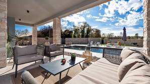 An outdoor patio area with a pool, wicker furniture, and a stone wall backdrop. - Villa Renata with Pool and Sauna (Kanfanar)
