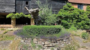 Surrounded by mature vegetation, this traditional building features a well-maintained garden area with a rustic stone wall.