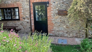 Relax on the bench outside Cider Cottage, surrounded by lush flowering plants.