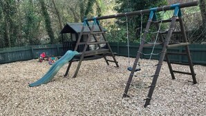 A playground with a slide, swings, and a small shelter. - Hayloft Cottage - Devon (Sidmouth)