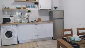 Eine kleine Küche mit Waschmaschine, Mikrowelle und Kühlschrank.