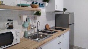 Eine moderne Küche mit weißen Schränken, einer Holzausziehtafel, einer Edelstahl-Spüle und einer eingebauten Mikrowelle.